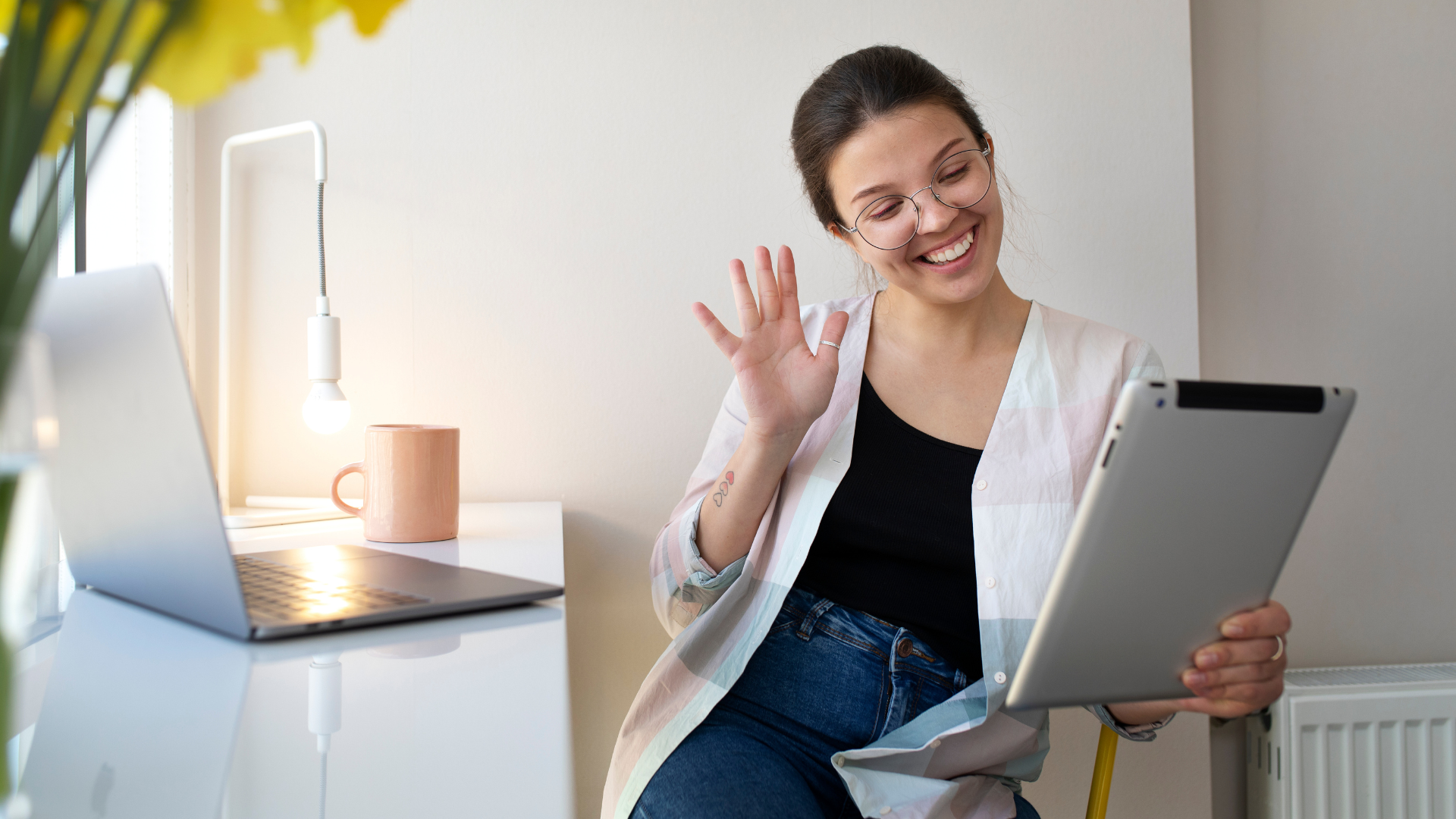 Mulher sorridente em videoconferência, utilizando um tablet em um ambiente de trabalho.
