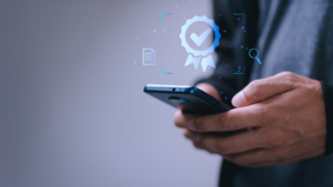 Contador segurando um smartphone enquanto interage com uma interface digital, que exibe um selo de verificação (checkmark) e um ícone de certificado.
